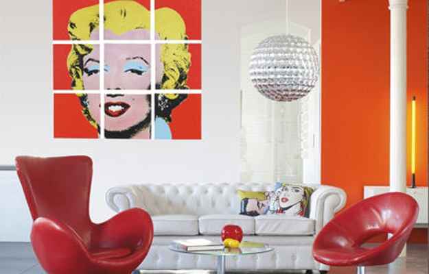 Uma das principais obras de Andy Warhol, que retrata a atriz Marilyn Monroe, as almofadas e os móveis coloridos decoram a sala com o estilo Pop Art (Reprodução/Internet)